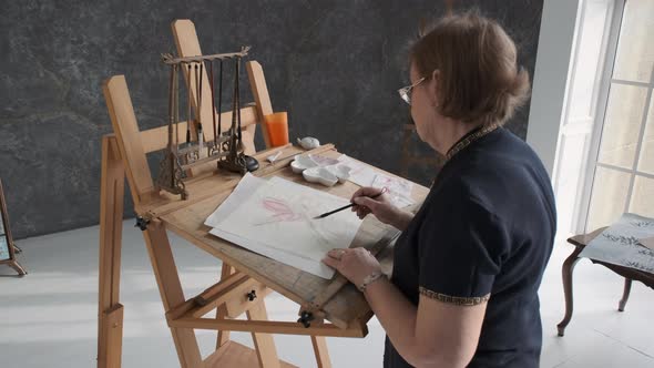 Elderly Woman is Painting Lotus in Art Studio alt