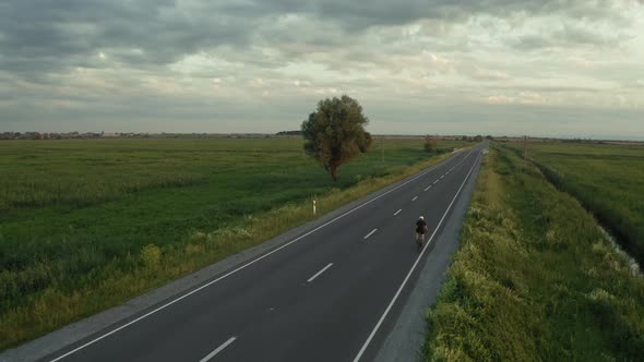A Cyclist is Riding Slowly Along the Highway alt