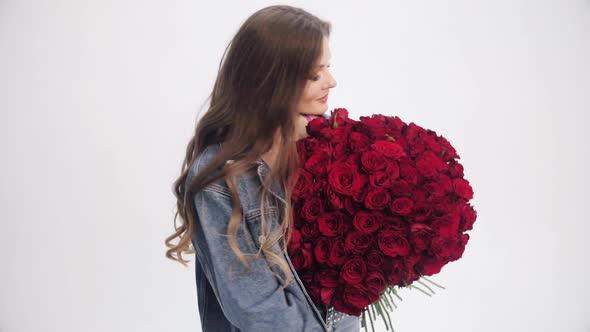 Brunette Lady with Long Hair Sniffing Bouquet of Red Roses