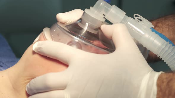 Doctor's hands are holding anesthesia mask on the patient's face