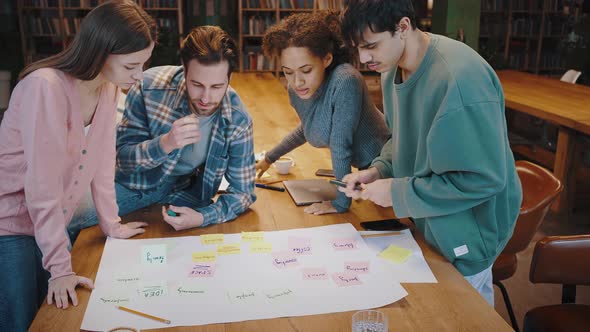 Young Multiethnic Businesspeople Collaborating on Marketing Research at Library alt