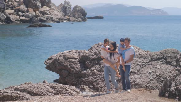 Happy family with two kids hands up on the beach near the sea. alt