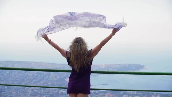 Tourist Woman with Waving Shawl on Wind on Mountain Viewpoint Top with Scenic Seascape alt