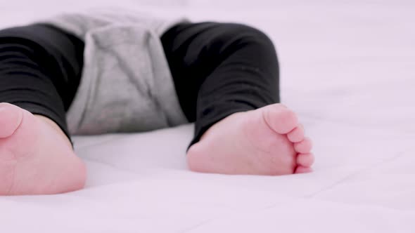 Close-up portrait of baby feet and a sleeping on bed during the daytime, pan view