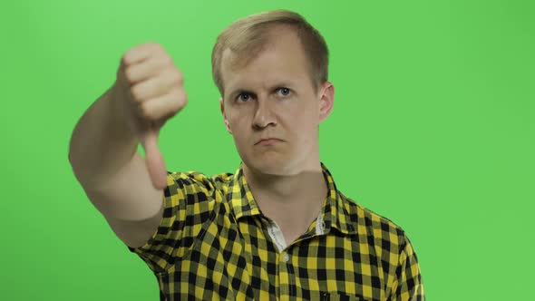 Caucasian Young Man in Yellow Shirt Showing No and Giving His Thumb Down alt