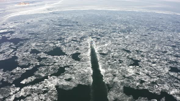 A Ferry Among Ice Floes on a Sunny Day in Winter From a Drone alt
