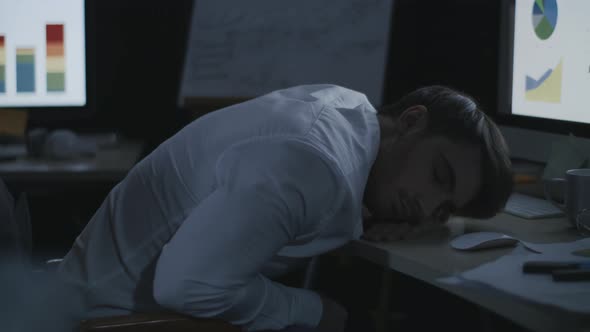 Tired Business Man Sleeping on Desk Front Computer Screen in Night Office. alt
