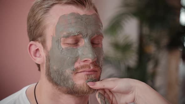 Female Hand Applying Clay Mask on Boyfriend Face. Caring Girlfriend Grooing Man. Concept Body Care