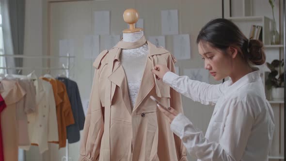 Young Asian Woman Fashion Designer Looking His Phone With Clothes On Mannequin Model alt