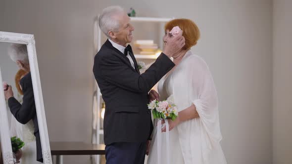 Charming Loving Senior Woman Admiring Man As Groom Putting Flower in Hair of Bride in Slow Motion alt