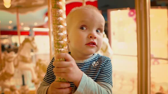 Close Up View of a Little Boy Having Fun on the Carousel for the First Time