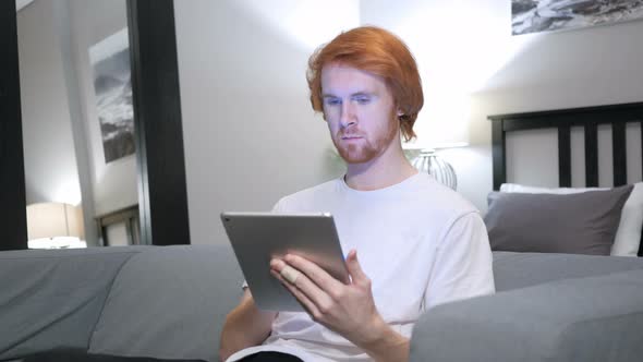 Online Shopping on Tablet PC by Sitting Redhead Man alt