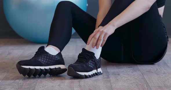 Young Girl Wearing Sneakers Before Workout, Sitting on Floor alt