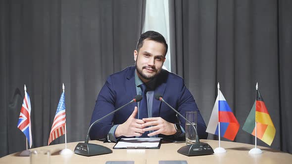 Handsome Caucasian Businessman Sit Speaking Into the Microphone at Meeting