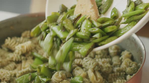 Cook adding green beans to pasta in pan alt