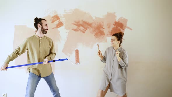 Excited Romantic Couple Fights with Paint Brush and Roller