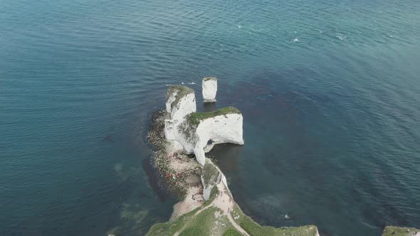rising pan down drone shot of Old Harry rocks chalk cliffs from the mainland alt