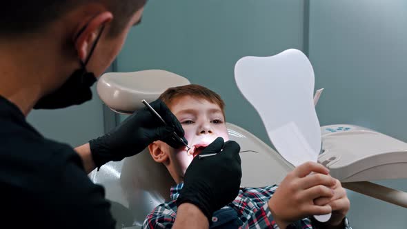 A Little Boy Having a Treatment in the Modern Dentistry - the Boy Holding a Mirror and Looking What alt