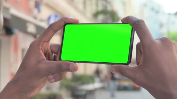 African Man Looking at Smartphone with Green Chroma Screen alt
