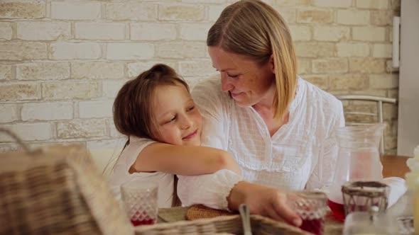 Smiling Daughter Embracing Mother While Having Food at Dining Table