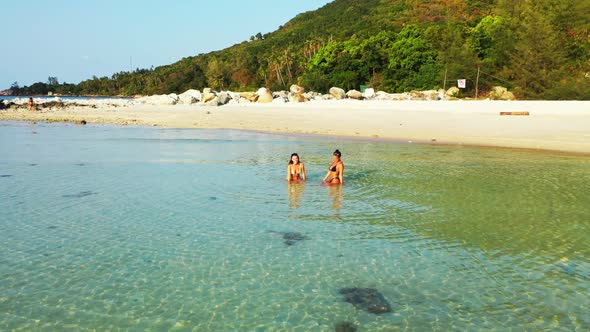 Girls happy together on idyllic shore beach lifestyle by blue green ocean and bright sandy backgroun alt