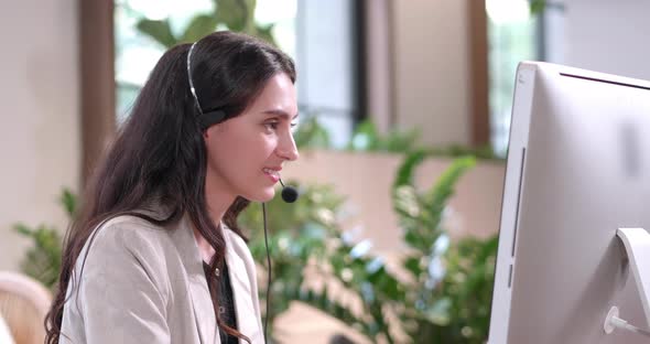 Businesswoman wearing headset working in office with computer alt