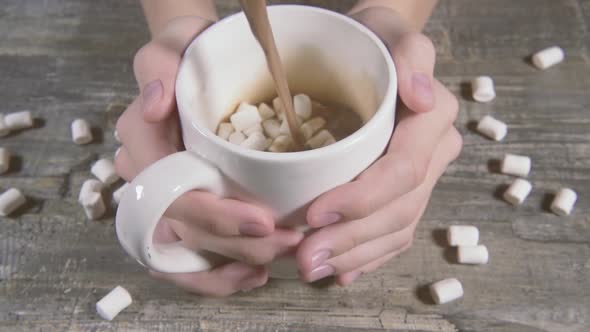 Slow Motion in the Hands of a White Mug with Marshmallows and Pouring Cocoa