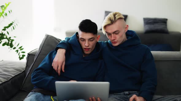 Loving Gay Couple Spend Time at Home Watching Movie Togather on Laptop alt