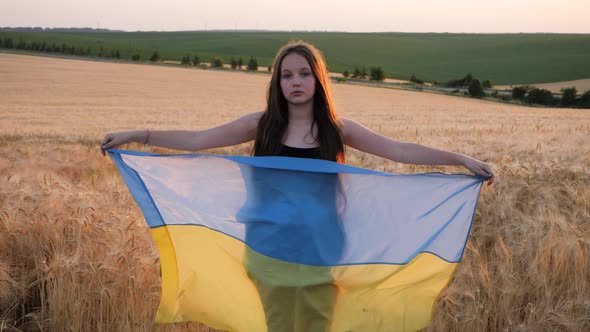 Pray for Ukraine. Child with Ukrainian flag in wheat field.