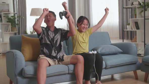 Asian Children With Joystick Game Play Video Game On Tv And Celebrating Victory alt