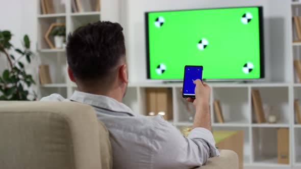 Man Using Smartphone and Watching TV with Green Screen alt
