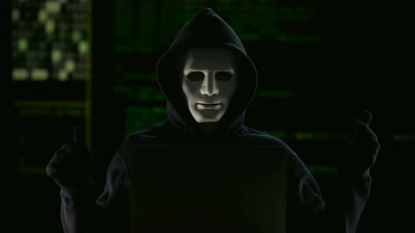 Hacker in mask and gloves breaking government servers alt
