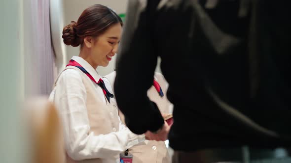 4K Woman flight attendant checking passenger boarding pass in airplane. alt