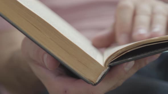 Close-up of Male Hands Leafing Through the Pages of the Book Indoors. Concept of Knowledge alt