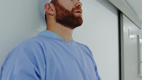 Close-up of worried Caucasian male doctor standing in the corridor alt
