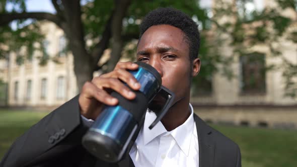 Young African American Man Drinking Morning Coffee From Thermos Looking at Camera with Confident alt