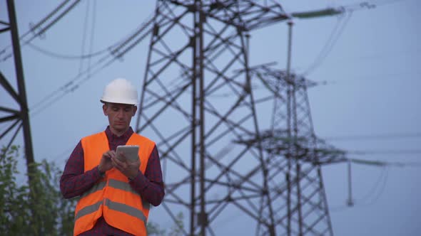 Engineer Inspects a Power Line Using Data From Electric Sensors on a Tablet