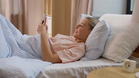 Happy Girl with Smartphone in Bed at Home alt