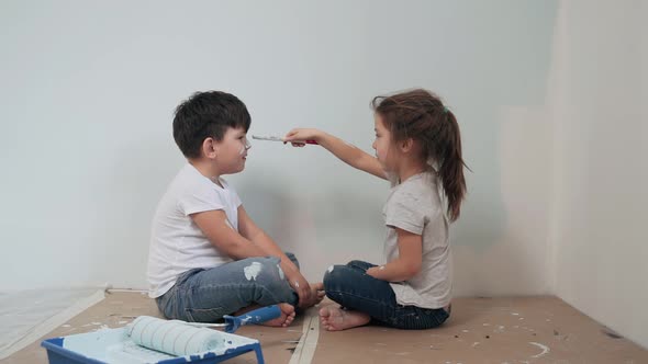 Caucasian Kids Paint the Walls Boy and Girl Took a Break and Have Fun Girl Paints a Brush on the Boy