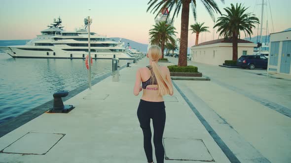 Back View of Blonde Sport Woman Jogging in Port