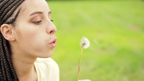 Young Beautiful Woman with Freckles Playing with a Dandelion Outdoor in Summer Day