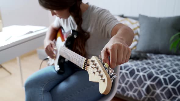 Young woman learning to tune electric guitar alt