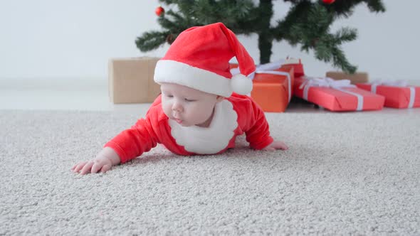 Cute Baby in Costume of Santa Claus, Looking a Gift alt