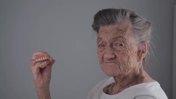 Elderly Woman Took Off Removable Dentures Shows to Camera and Smiles alt