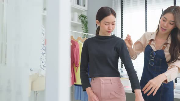 Asian tailor woman measure customer's body to making her new clothes. alt