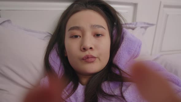 Phone Camera POV of 20s Asian Woman Typing Message Lying in Bed alt