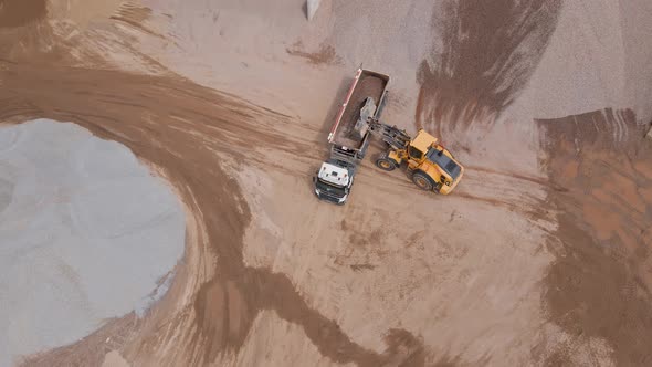 Excavator Loading Sand Into Large Truck Aerial View alt