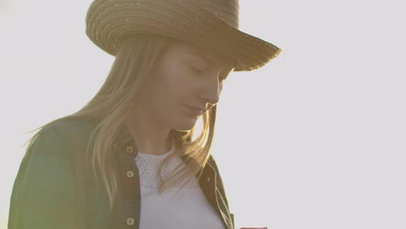 A Female Farmer in a Plaid Shirt with a Tablet Computer in Her Hands is Walking Across a Wheat Field alt