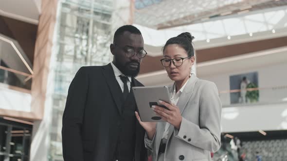 Colleagues with Tablet Discussing Work in Lobby alt