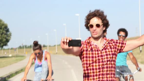 Three young adults having fun cycling and taking selfies alt
